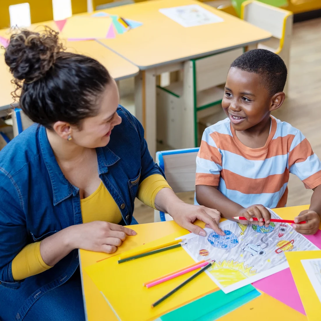 Preschool teacher talking to a boy in the classroom